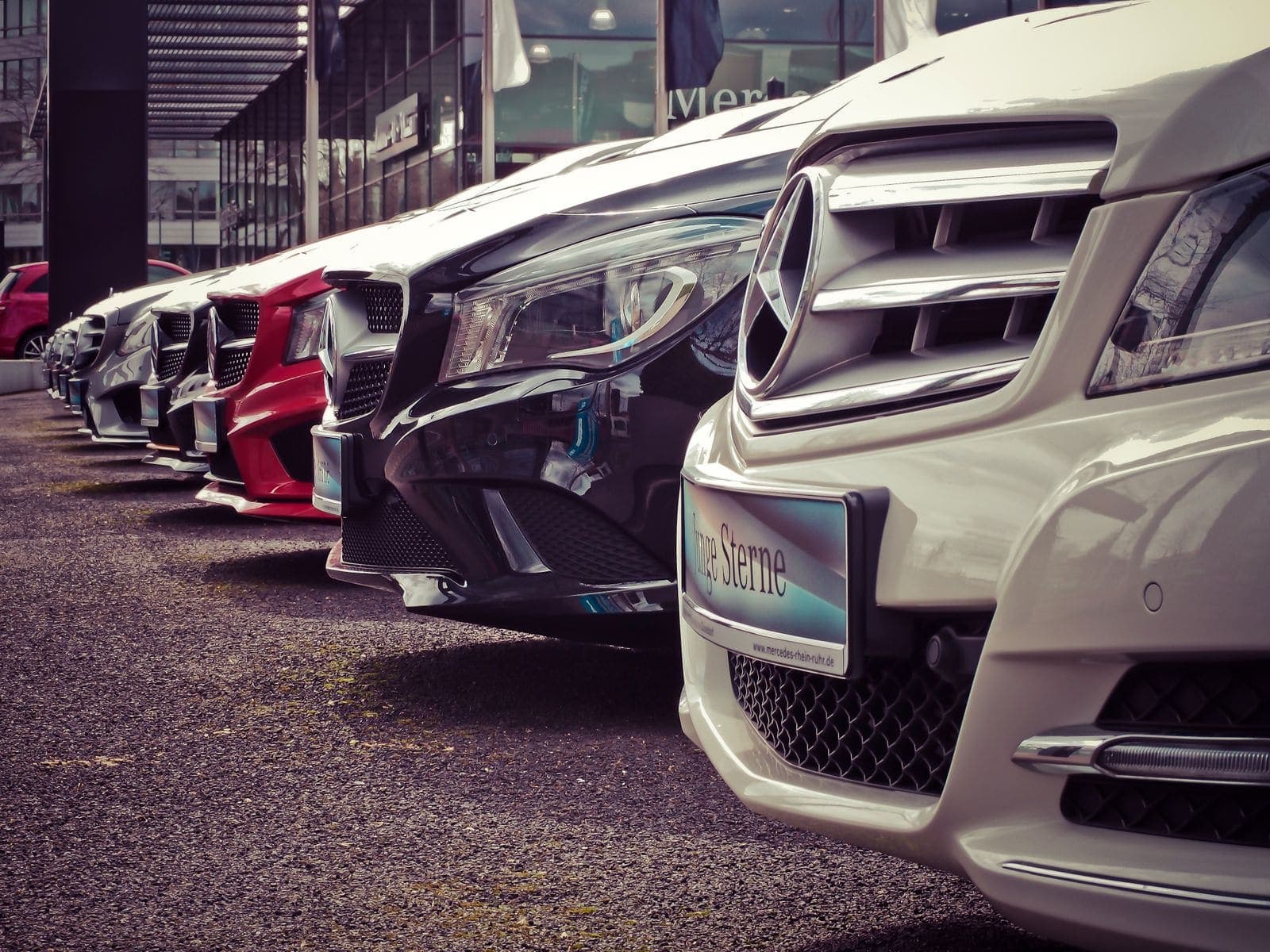Luxury vehicles lined up outside a glass-fronted car dealership