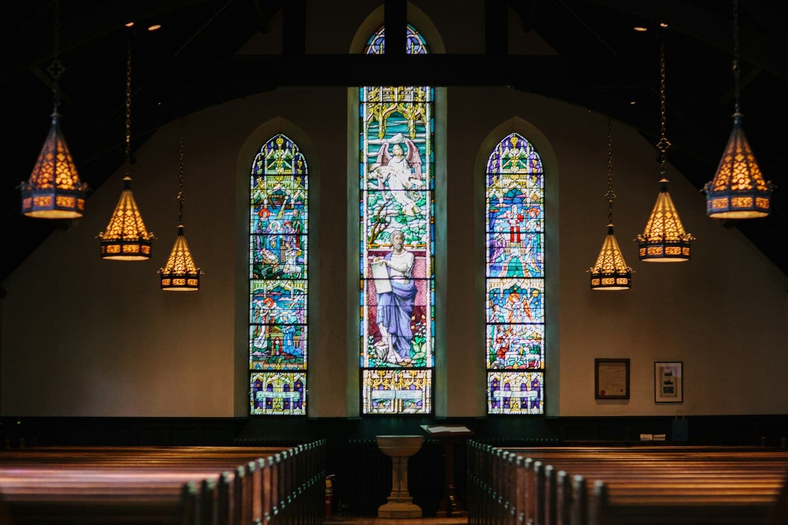 Church sanctuary with polished wooden pews and stained-glass windows