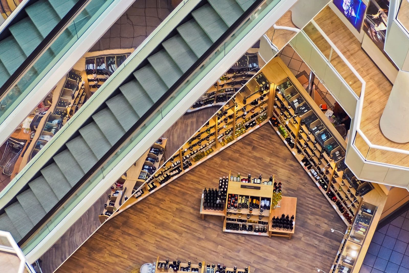 Multi-level retail mall space with polished wood floors and glass railings